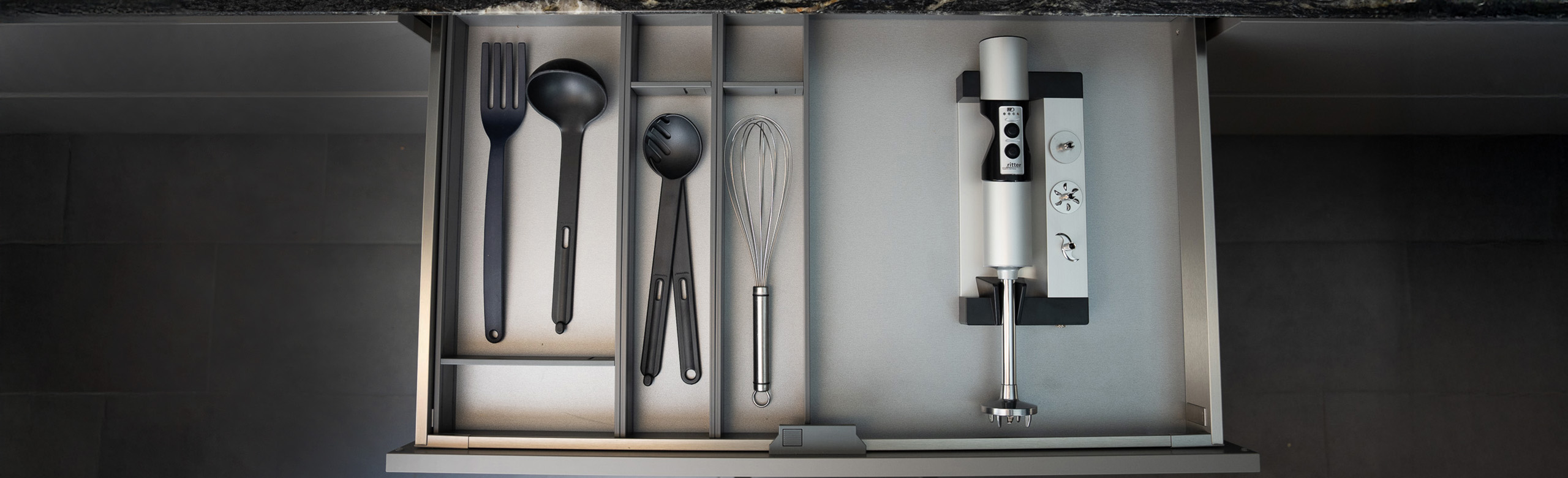 Ein Bild von einer Schublade mit einem Einbau-Stabmixer und anderem Besteck.