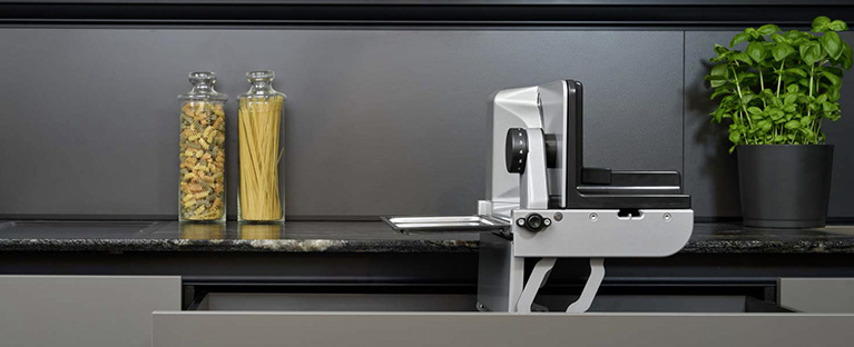 Ein Bild von einem Einbau-Allesschneider, der aus einer Küchenschublade herauskommt.