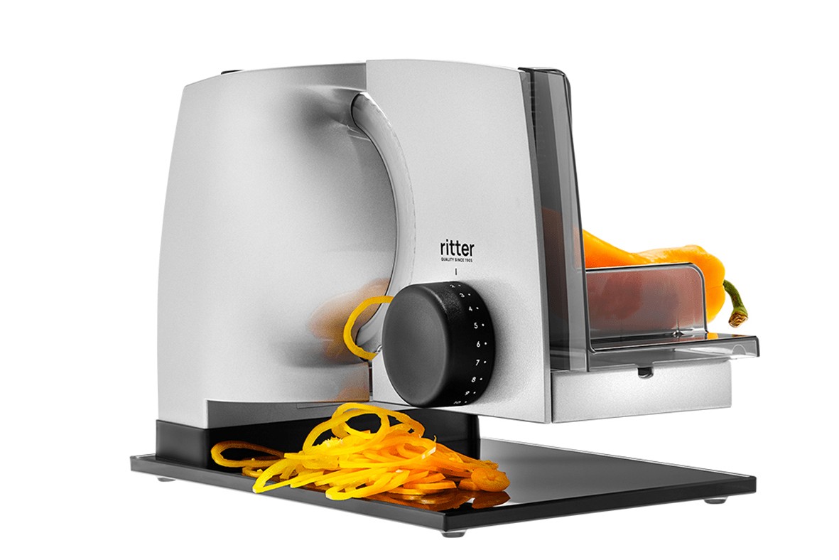 Electric food slicer in silver, angled view with sliced food