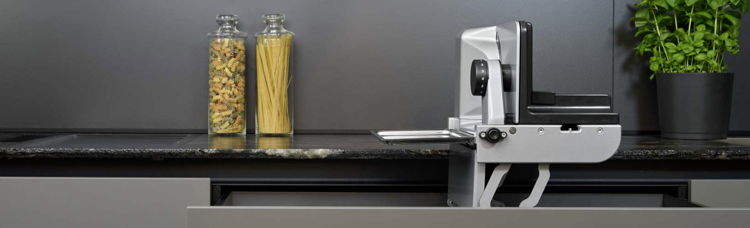 Ein Bild von einem Einbau-Allesschneider, der aus einer Küchenschublade hervorkommt.