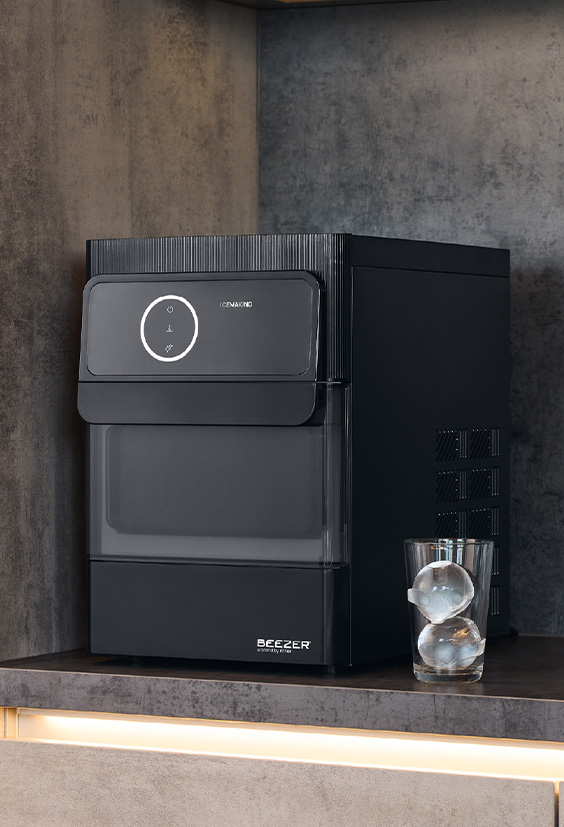 Schwarze Eiskugelmaschine in Küche daneben Glas mit Eiskugeln gefüllt