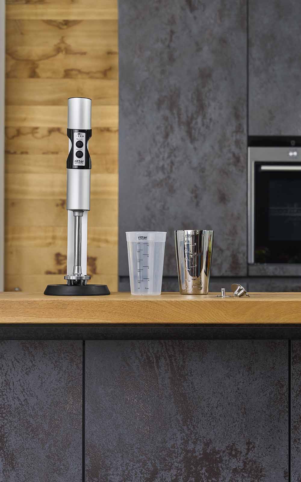 A picture of a silver hand blender and two measuring jugs standing in a kitchen. A picture of a silver hand blender and two measuring jugs standing in a kitchen.