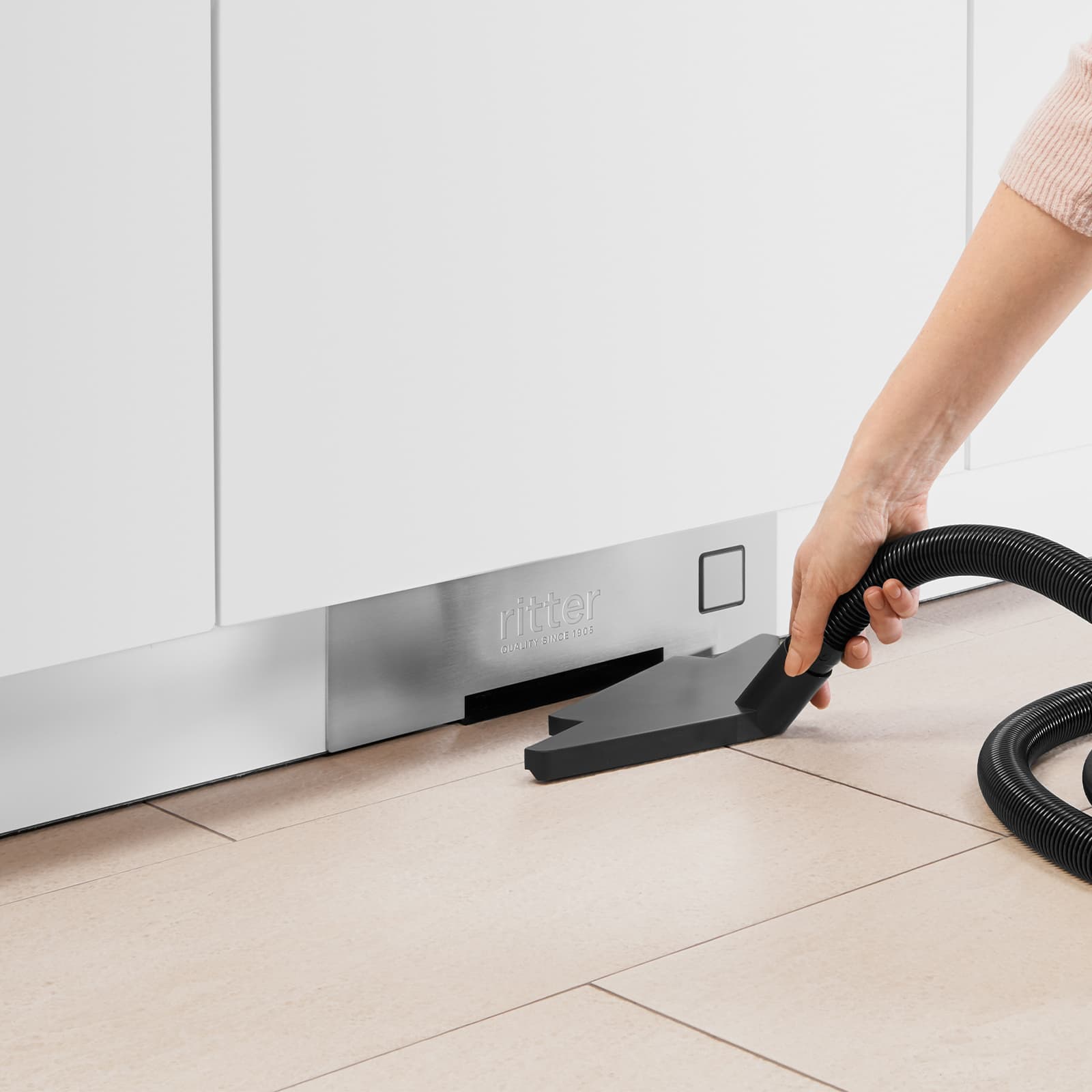 Ein Bild von einem Staubsaugerschlauch, der in den Einbau-Sockelsauger gesteckt wird.