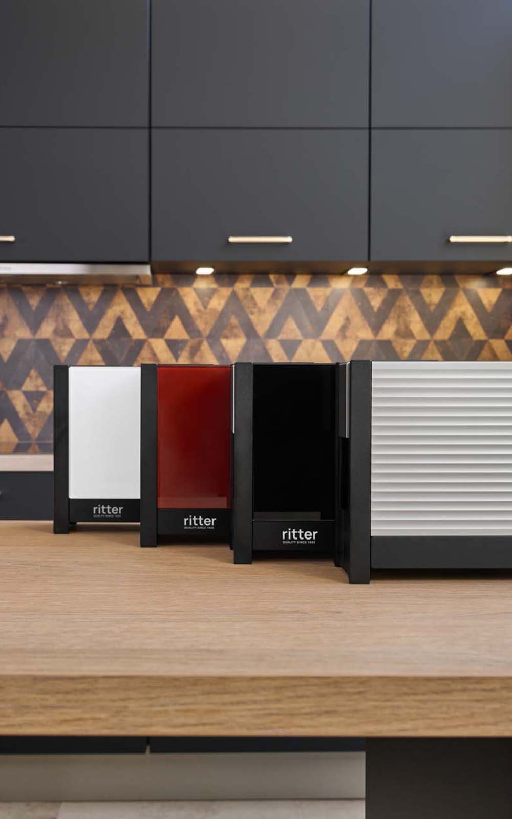 Ein Bild von einem Aluminium-, einem weißen, einem roten und einem schwarzen Toaster, die aufgereiht , hintereinander, in einer Küche stehen. Ein Bild von einem Aluminium-, einem weißen, einem roten und einem schwarzen Toaster, die aufgereiht , hintereinander, in einer Küche stehen.