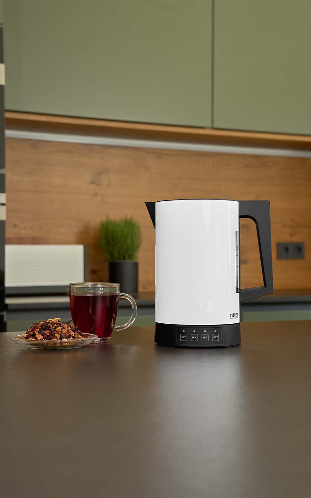 Ein Bild des weißen Wasserkochers, der auf einer Küchenplattform, neben einer Tasse Tee, steht. Ein Bild des weißen Wasserkochers, der auf einer Küchenplattform, neben einer Tasse Tee, steht.