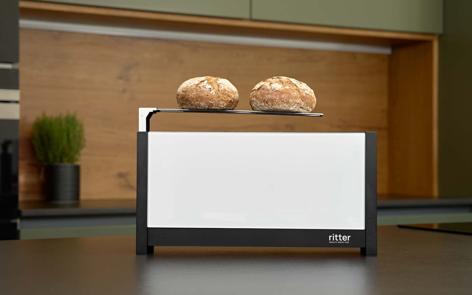 Ein Bild eines weißen Toasters, der Brote auf der Brötchenauflage liegen hat und auf einer Küchenplattform steht.