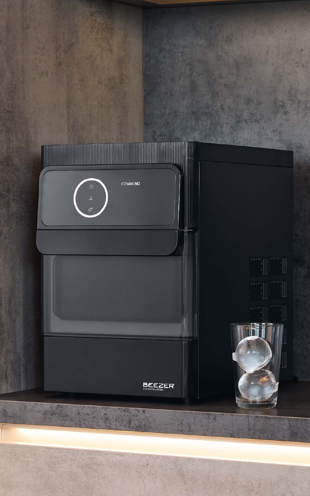 Schwarze Eiskugelmaschine, daneben ein Glas mit zwei Eiskugeln drin.